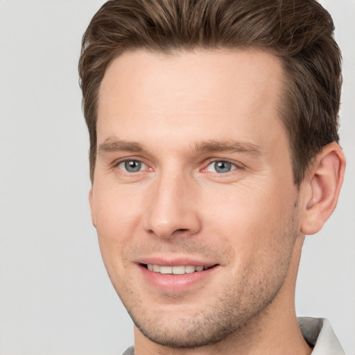 Joyful white young-adult male with short  brown hair and grey eyes