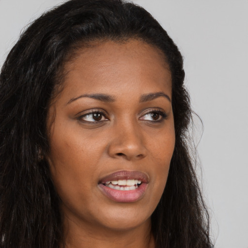 Joyful black young-adult female with long  brown hair and brown eyes
