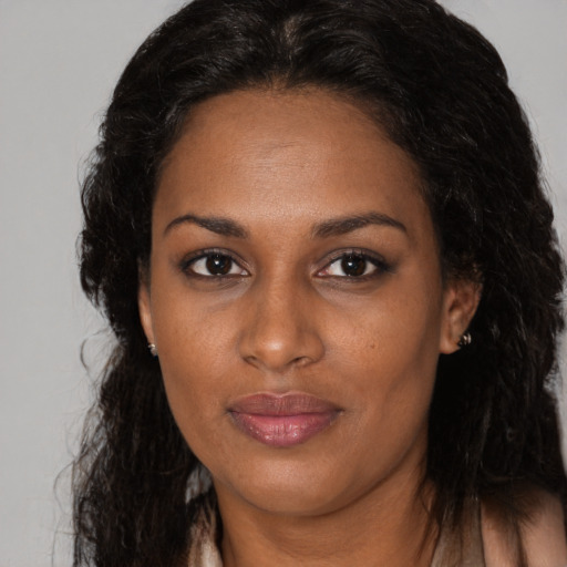 Joyful black adult female with long  brown hair and brown eyes
