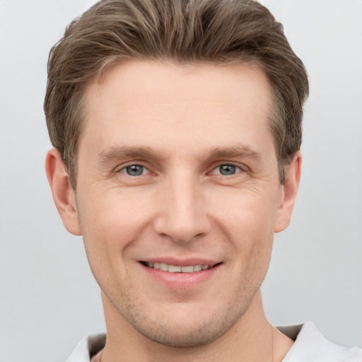 Joyful white young-adult male with short  brown hair and grey eyes