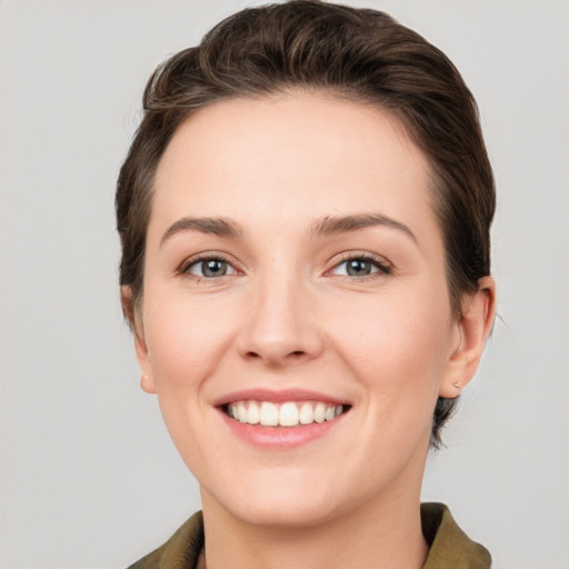 Joyful white young-adult female with short  brown hair and green eyes