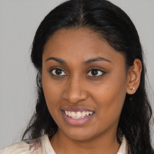 Joyful black young-adult female with long  brown hair and brown eyes