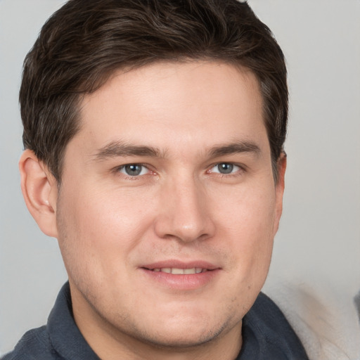 Joyful white young-adult male with short  brown hair and grey eyes