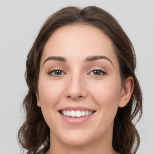 Joyful white young-adult female with long  brown hair and grey eyes