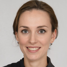 Joyful white young-adult female with medium  brown hair and grey eyes