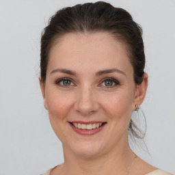 Joyful white young-adult female with medium  brown hair and grey eyes