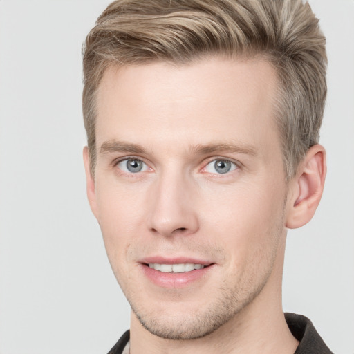 Joyful white young-adult male with short  brown hair and grey eyes