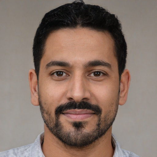 Joyful latino young-adult male with short  black hair and brown eyes