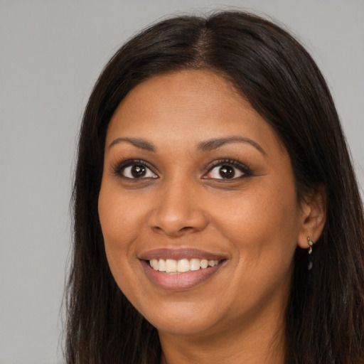 Joyful black young-adult female with long  brown hair and brown eyes