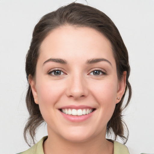 Joyful white young-adult female with medium  brown hair and grey eyes