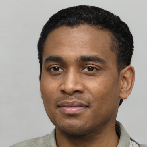 Joyful black young-adult male with short  black hair and brown eyes