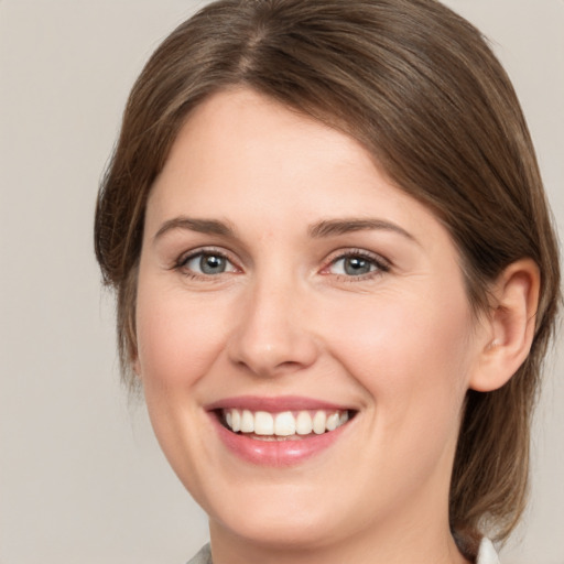 Joyful white young-adult female with medium  brown hair and grey eyes