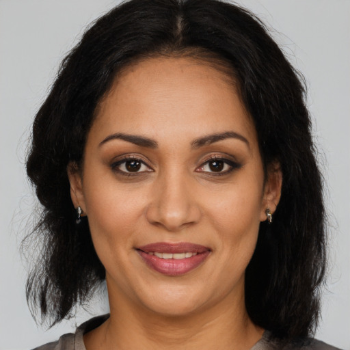 Joyful latino adult female with medium  brown hair and brown eyes