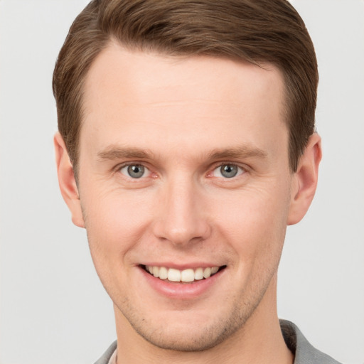 Joyful white young-adult male with short  brown hair and grey eyes