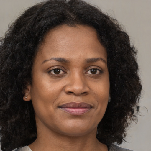 Joyful black young-adult female with long  brown hair and brown eyes