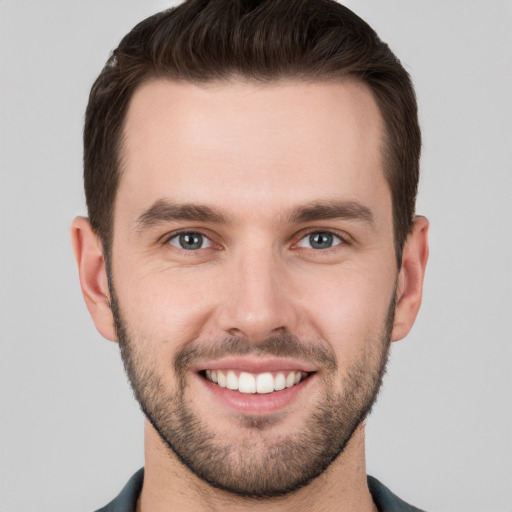 Joyful white young-adult male with short  brown hair and grey eyes