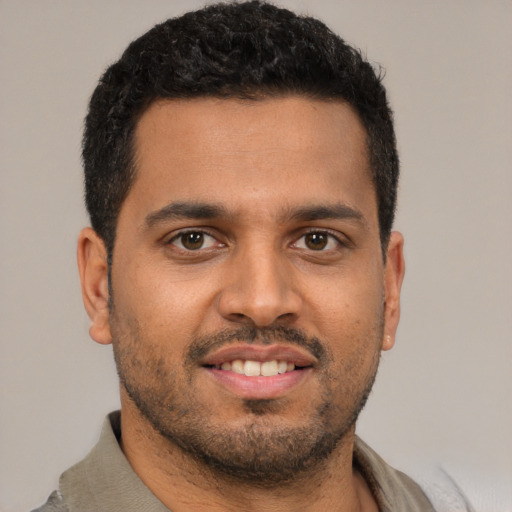 Joyful black young-adult male with short  brown hair and brown eyes