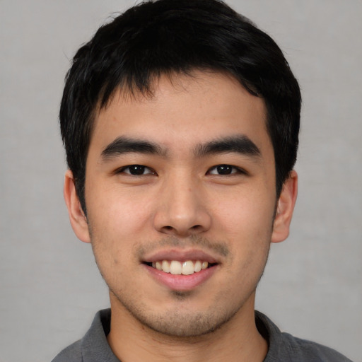 Joyful asian young-adult male with short  black hair and brown eyes
