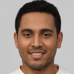 Joyful latino young-adult male with short  brown hair and brown eyes