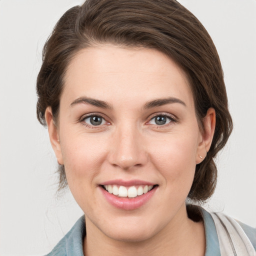 Joyful white young-adult female with medium  brown hair and grey eyes