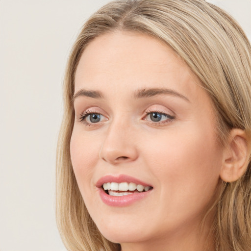 Joyful white young-adult female with long  brown hair and blue eyes