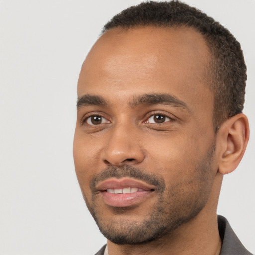 Joyful black young-adult male with short  brown hair and brown eyes