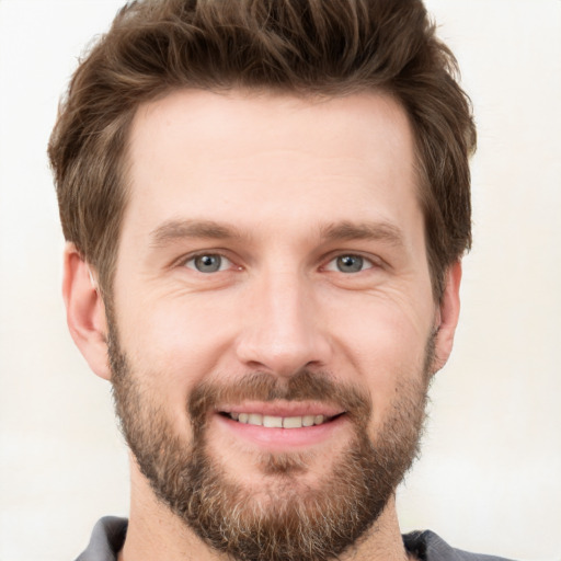 Joyful white young-adult male with short  brown hair and grey eyes