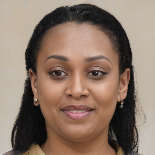 Joyful black young-adult female with long  brown hair and brown eyes