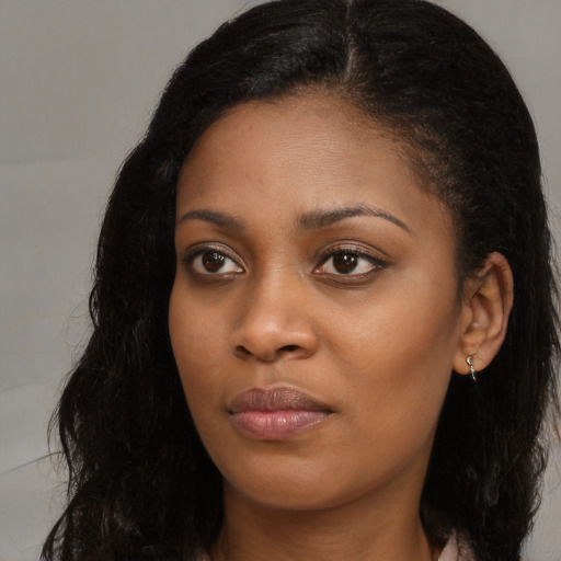 Joyful black young-adult female with long  brown hair and brown eyes