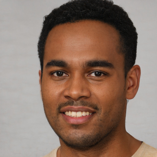 Joyful black young-adult male with short  brown hair and brown eyes