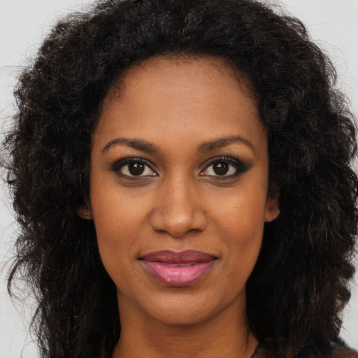 Joyful black young-adult female with long  brown hair and brown eyes
