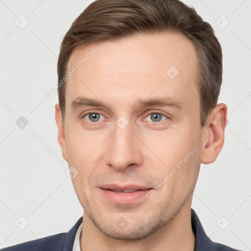 Joyful white young-adult male with short  brown hair and grey eyes