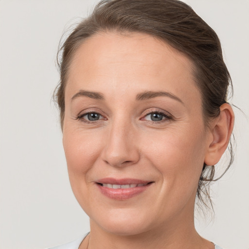 Joyful white young-adult female with medium  brown hair and grey eyes