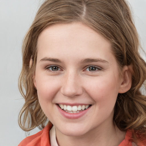 Joyful white young-adult female with medium  brown hair and grey eyes