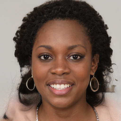 Joyful black young-adult female with long  black hair and brown eyes