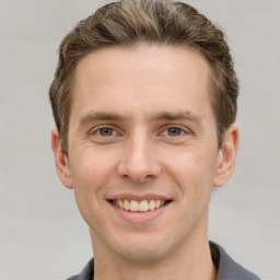 Joyful white young-adult male with short  brown hair and grey eyes