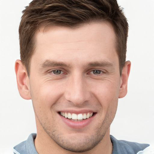 Joyful white young-adult male with short  brown hair and grey eyes