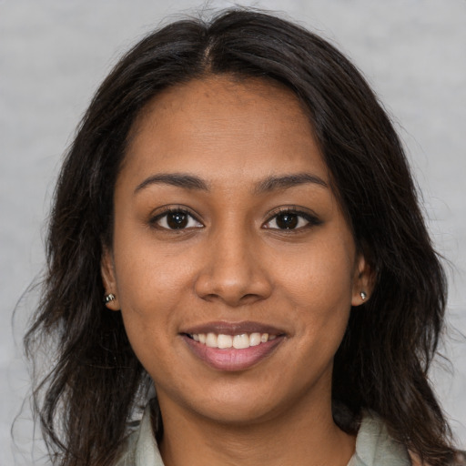 Joyful black young-adult female with long  brown hair and brown eyes