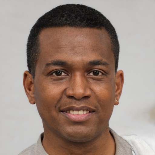 Joyful black young-adult male with short  brown hair and brown eyes