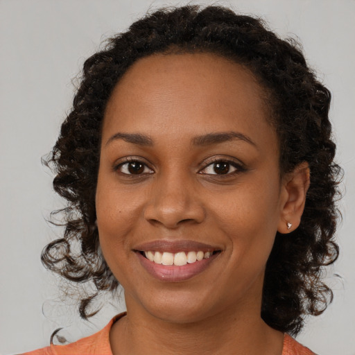 Joyful black young-adult female with long  brown hair and brown eyes