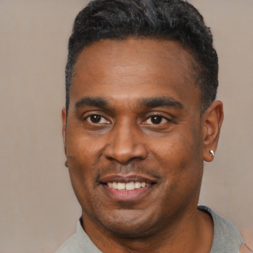 Joyful black young-adult male with short  black hair and brown eyes
