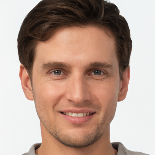 Joyful white young-adult male with short  brown hair and grey eyes