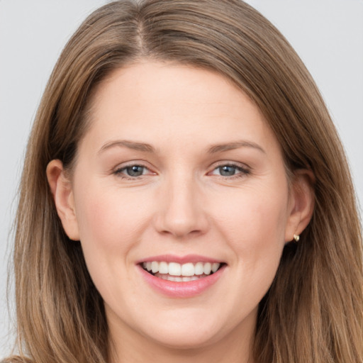 Joyful white young-adult female with long  brown hair and grey eyes