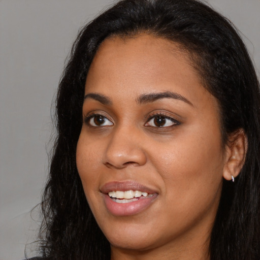 Joyful black young-adult female with long  black hair and brown eyes
