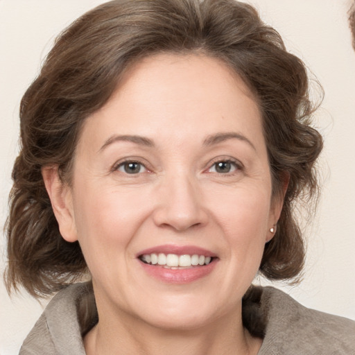 Joyful white adult female with medium  brown hair and grey eyes