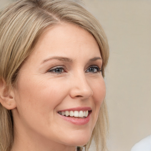 Joyful white young-adult female with long  blond hair and grey eyes