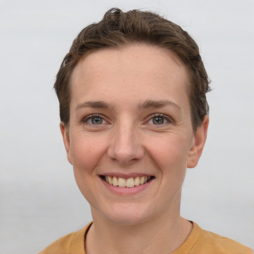 Joyful white young-adult female with short  brown hair and grey eyes