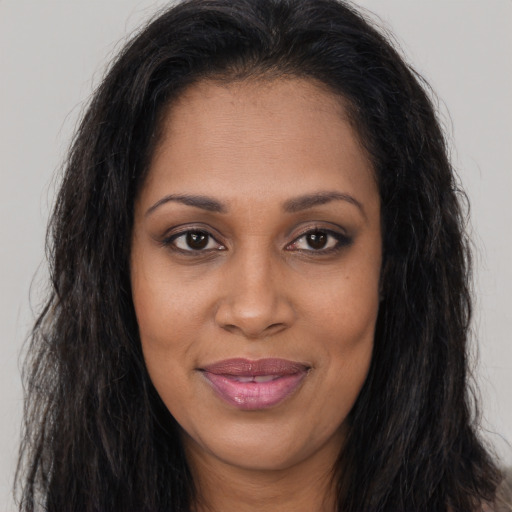 Joyful black young-adult female with long  brown hair and brown eyes