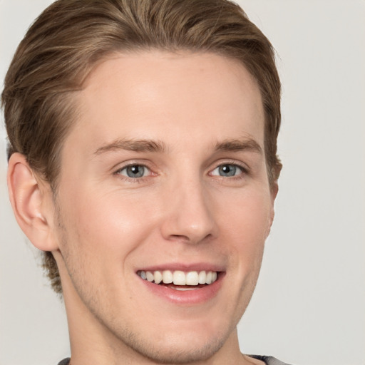 Joyful white young-adult male with short  brown hair and grey eyes