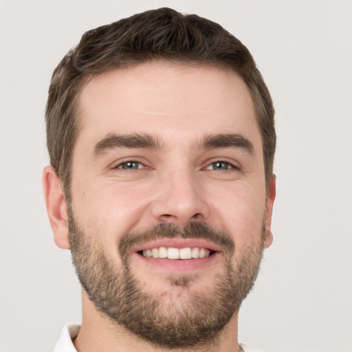 Joyful white young-adult male with short  brown hair and grey eyes